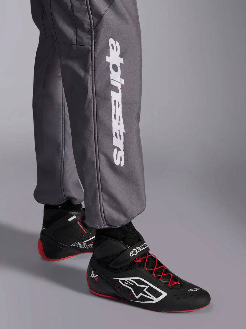 Close-up leg view of a driver wearing the Alpinestars KMX-9 V3 Graphic 5 Kart Suit in Dark Gray/Black color at FAST RACER
